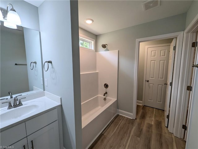 bathroom featuring washtub / shower combination, wood-type flooring, and vanity