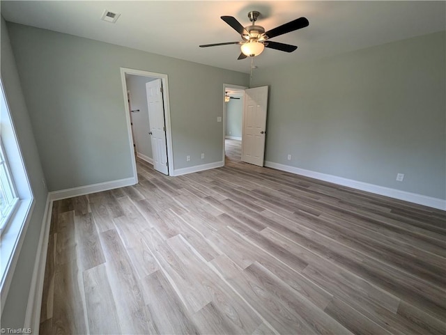 unfurnished bedroom featuring visible vents, baseboards, wood finished floors, and a ceiling fan