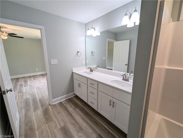 full bathroom with a sink, baseboards, wood finished floors, and double vanity
