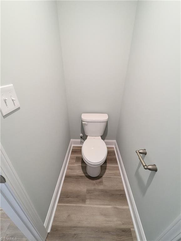 bathroom featuring toilet, wood finished floors, and baseboards