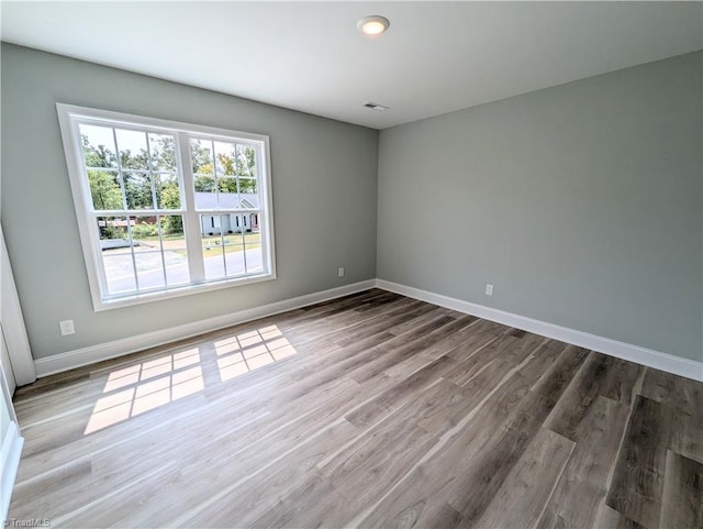 unfurnished room with visible vents, baseboards, and wood finished floors