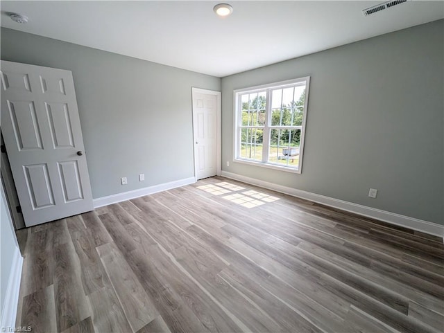 spare room with visible vents, baseboards, and wood finished floors