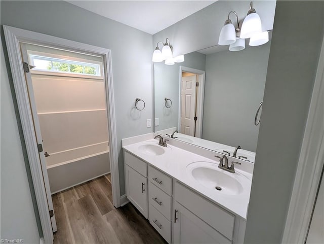 full bath featuring double vanity, wood finished floors, and a sink