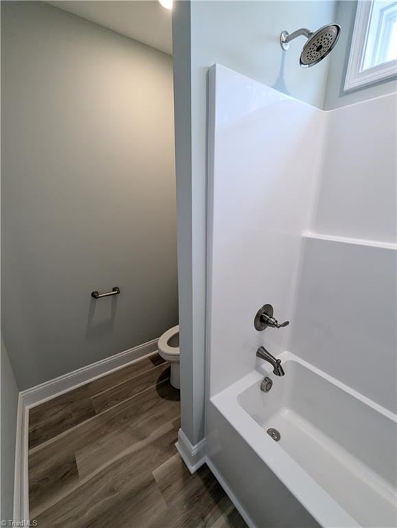 full bathroom featuring baseboards, toilet, wood finished floors, and bathtub / shower combination