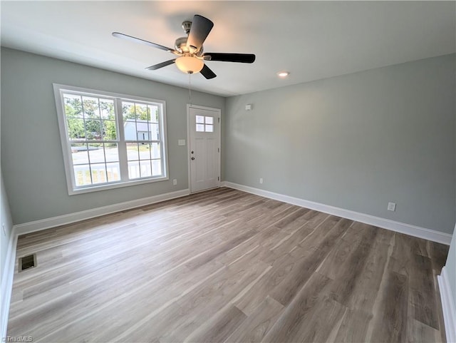 empty room with a ceiling fan, visible vents, wood finished floors, and baseboards