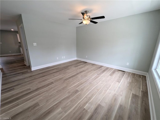 spare room featuring wood finished floors, baseboards, and ceiling fan