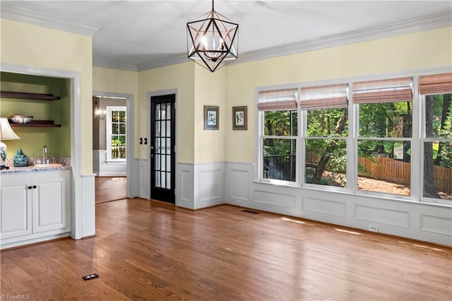 1420 Thornhill Ln, Winston-Salem, NC 27106 - unfurnished dining area with a chandelier, healthy amount of natural light, light wood-style flooring, a wainscoted wall, and ornamental molding