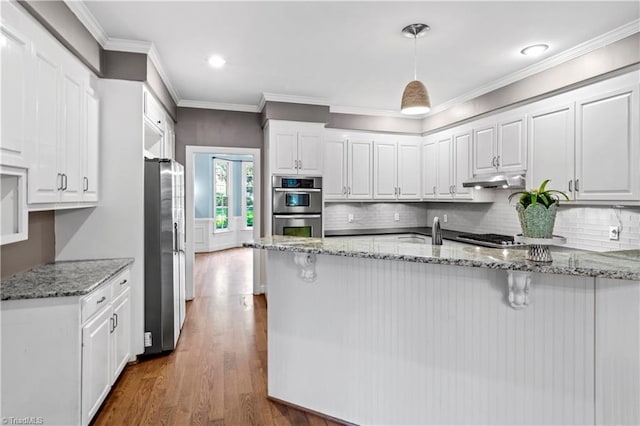1420 Thornhill Ln, Winston-Salem, NC 27106 - kitchen with appliances with stainless steel finishes, a peninsula, white cabinets, wood finished floors, and light stone countertops