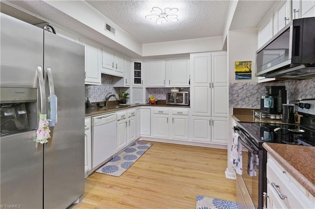2429 Cypress Ct, High Point, NC 27265 - kitchen featuring appliances with stainless steel finishes, a textured ceiling, white cabinets, light wood-style flooring, and dark countertops