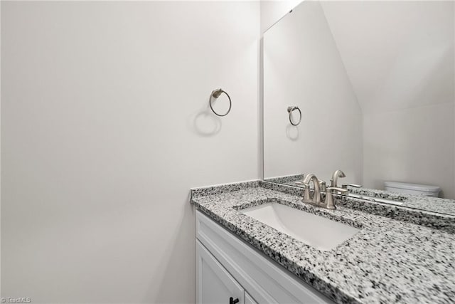 bathroom featuring lofted ceiling, toilet, and vanity