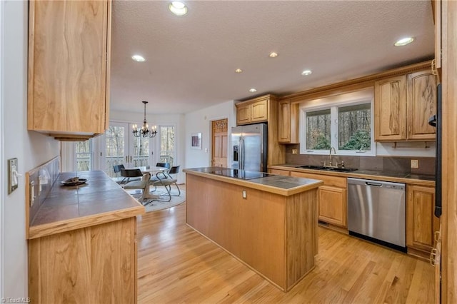 kitchen featuring sink, decorative light fixtures, light hardwood / wood-style flooring, a kitchen island, and stainless steel appliances