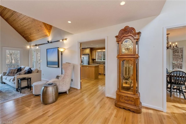 living area featuring a notable chandelier, lofted ceiling, light hardwood / wood-style flooring, and wooden ceiling