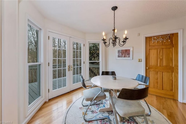 dining space featuring french doors, a chandelier, and light wood-type flooring