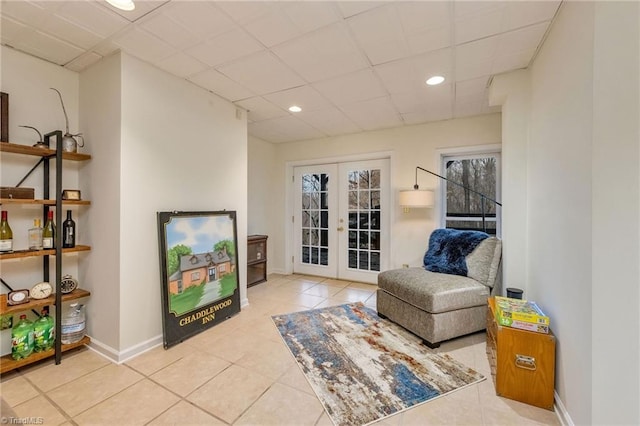 living area with light tile patterned flooring, a drop ceiling, and french doors