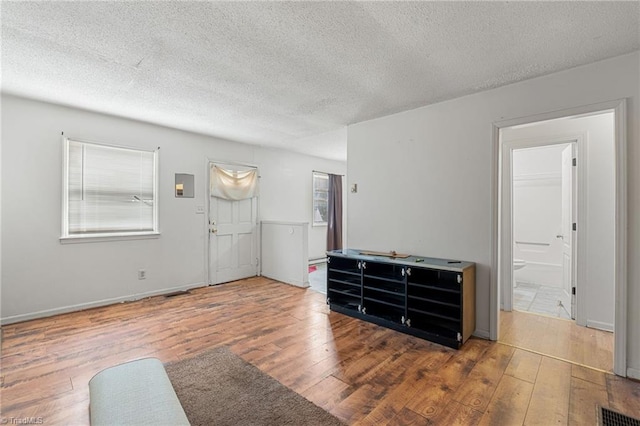 unfurnished living room featuring visible vents, a textured ceiling, and hardwood / wood-style floors