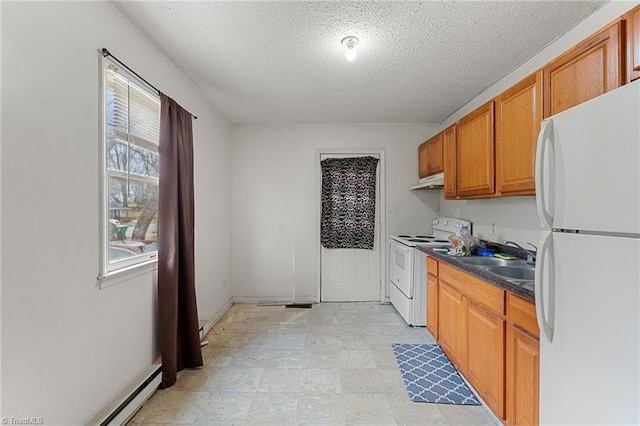 kitchen with dark countertops, under cabinet range hood, brown cabinets, white appliances, and a sink