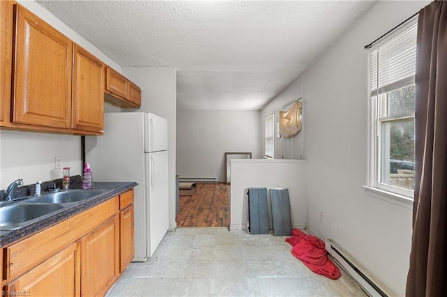 kitchen with dark countertops, a sink, brown cabinets, and a baseboard radiator