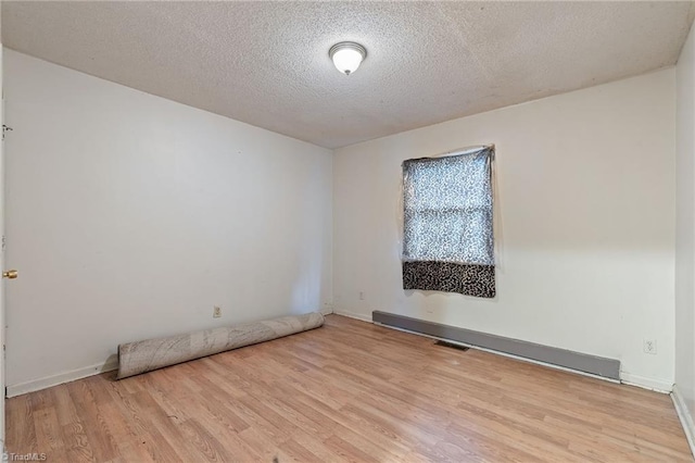 unfurnished room featuring visible vents, a textured ceiling, baseboards, and wood finished floors