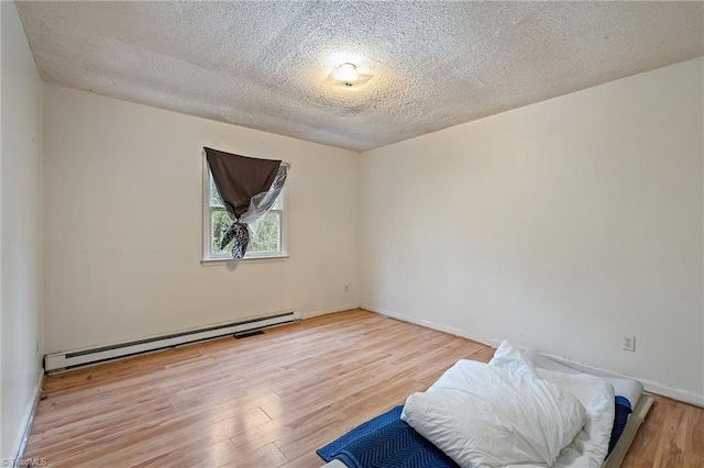 bedroom with a textured ceiling, wood finished floors, baseboards, and a baseboard radiator