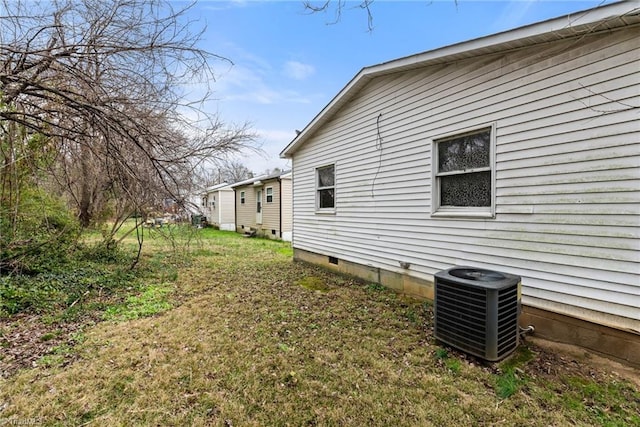 view of side of property featuring central air condition unit, a yard, and crawl space