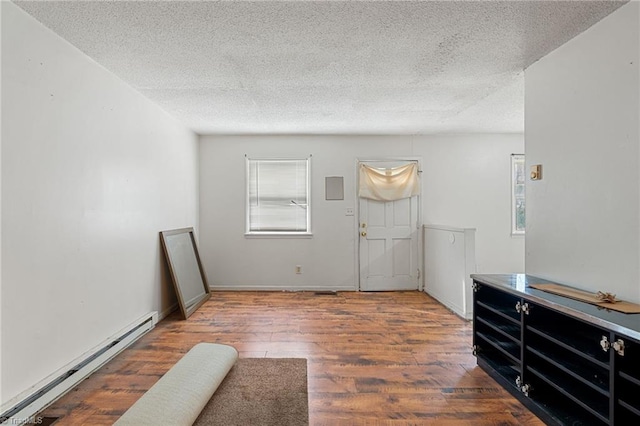 entryway featuring baseboard heating, a healthy amount of sunlight, wood finished floors, and a textured ceiling