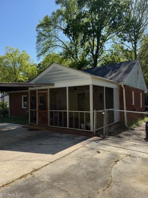 view of front of house featuring a sunroom, brick siding, and concrete driveway