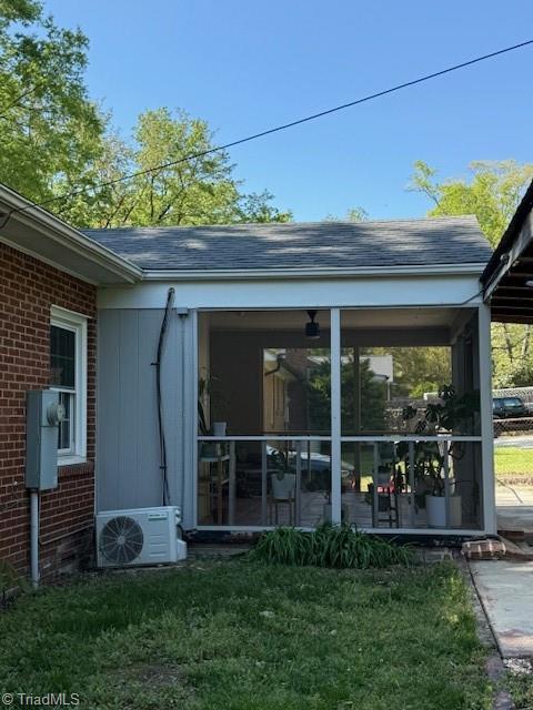 back of property with brick siding, a sunroom, ac unit, and a lawn