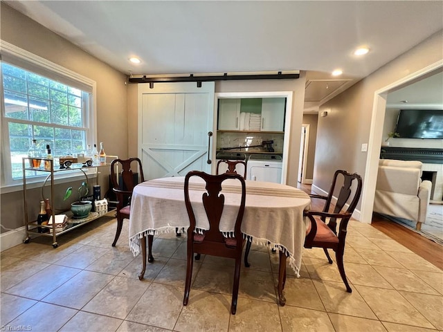 tiled dining space featuring washer / clothes dryer and a barn door