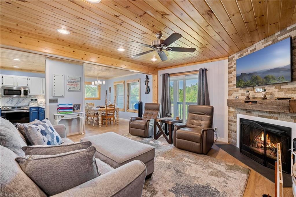 living room featuring ceiling fan, a fireplace, wooden ceiling, and light hardwood / wood-style floors