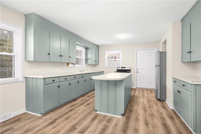 kitchen with a kitchen island, appliances with stainless steel finishes, and light hardwood / wood-style floors