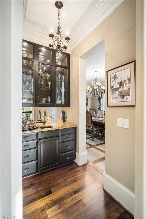 bar with an inviting chandelier, decorative light fixtures, dark hardwood / wood-style flooring, and ornamental molding