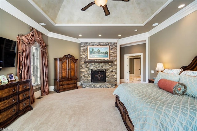 bedroom featuring light colored carpet, ceiling fan, a stone fireplace, crown molding, and a raised ceiling