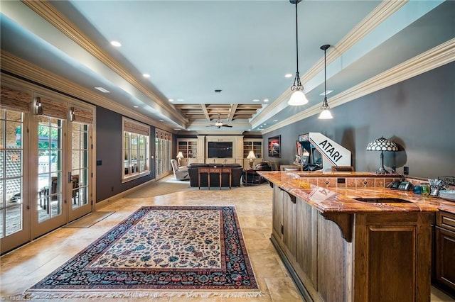 kitchen with decorative light fixtures, a tray ceiling, light tile flooring, and ornamental molding