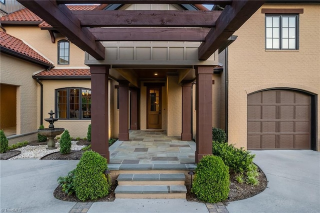 view of exterior entry featuring a pergola and a garage