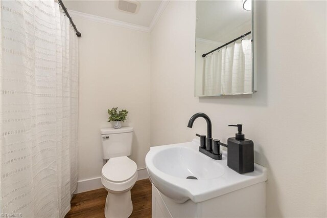 full bath with wood finished floors, baseboards, a sink, crown molding, and toilet