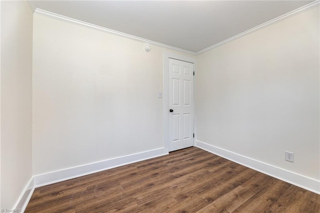 empty room featuring dark wood-style flooring, baseboards, and ornamental molding