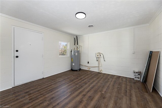 empty room featuring visible vents, electric water heater, dark wood finished floors, ornamental molding, and concrete block wall