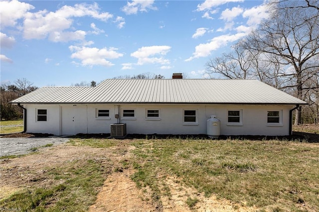 rear view of property with a standing seam roof, cooling unit, metal roof, and a chimney