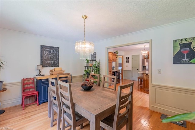 1160 Flinty Knoll Rd, Pinnacle, NC 27043 - dining area featuring crown molding, a chandelier, light wood finished floors, wainscoting, and a decorative wall
