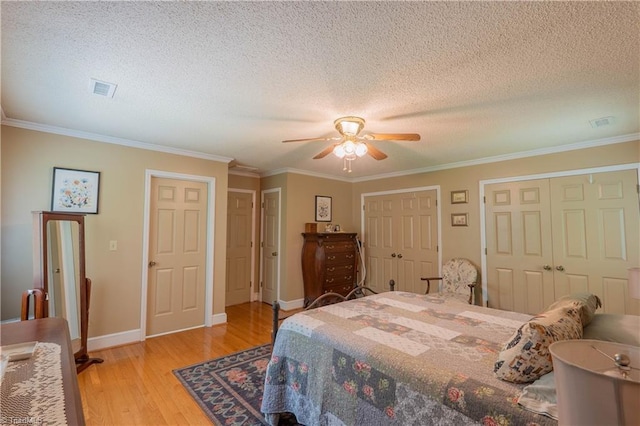 1160 Flinty Knoll Rd, Pinnacle, NC 27043 - bedroom with multiple closets, a textured ceiling, light wood-style flooring, crown molding, and baseboards