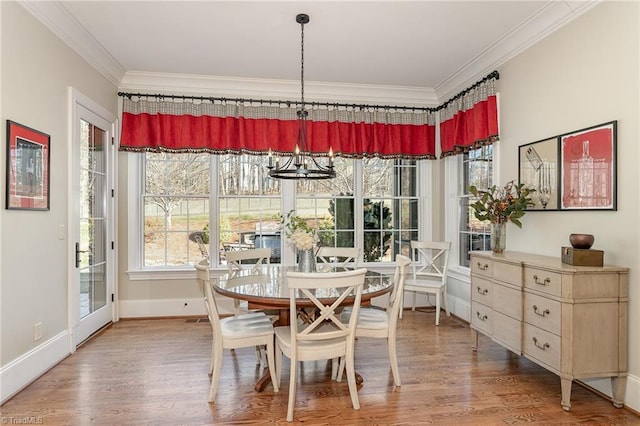 dining area with wood-type flooring, ornamental molding, and an inviting chandelier