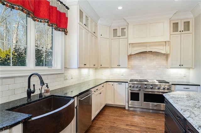 kitchen featuring sink, crown molding, dark wood-type flooring, appliances with stainless steel finishes, and dark stone counters