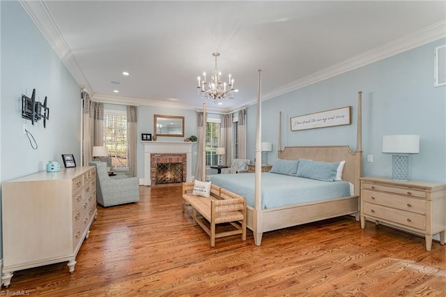 bedroom with a notable chandelier, a brick fireplace, crown molding, and light hardwood / wood-style floors