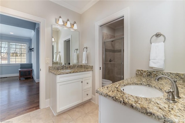 bathroom featuring toilet, a shower with shower door, crown molding, vanity, and tile patterned flooring