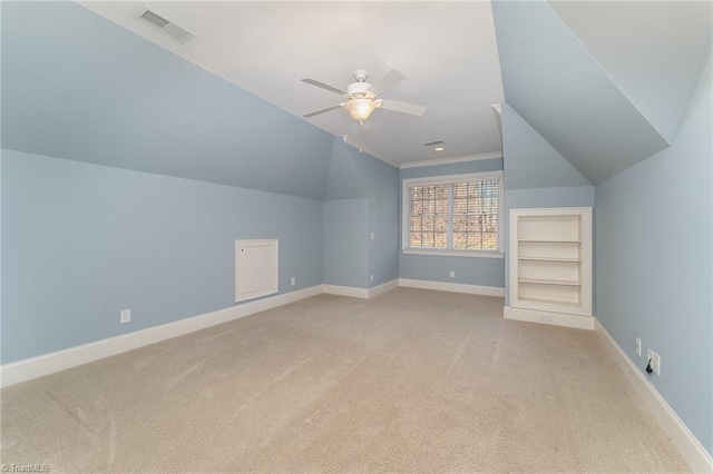 additional living space with light carpet, built in features, ceiling fan, and lofted ceiling