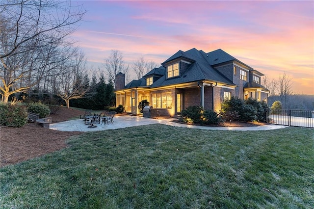 property exterior at dusk featuring a patio area and a lawn