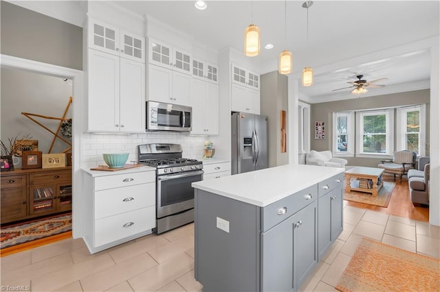 kitchen with gray cabinets, appliances with stainless steel finishes, white cabinetry, a kitchen island, and decorative light fixtures