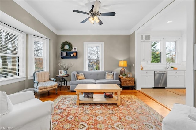 living room with ornamental molding, light hardwood / wood-style floors, and ceiling fan