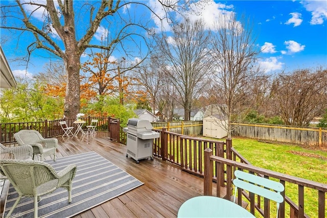 wooden deck featuring a grill, a yard, and a storage unit