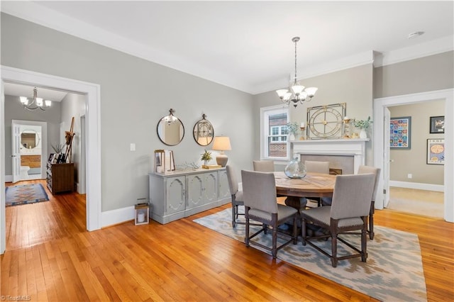 dining room with ornamental molding, a chandelier, and light hardwood / wood-style floors